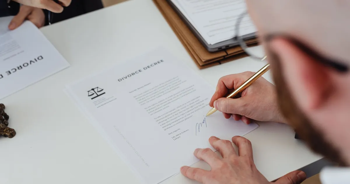 Hands signing a real estate contract at a closing table