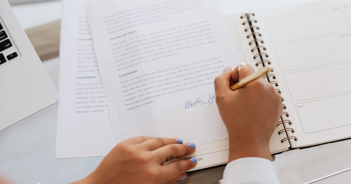 Hands signing a real estate contract at a closing table